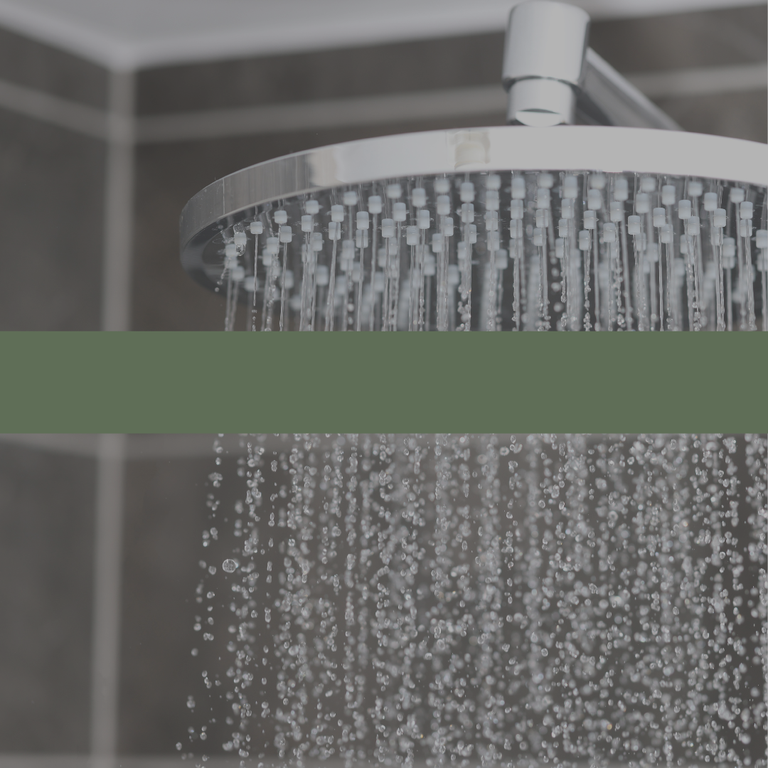 Close-up of a shower head with water droplets in a bathroom setting